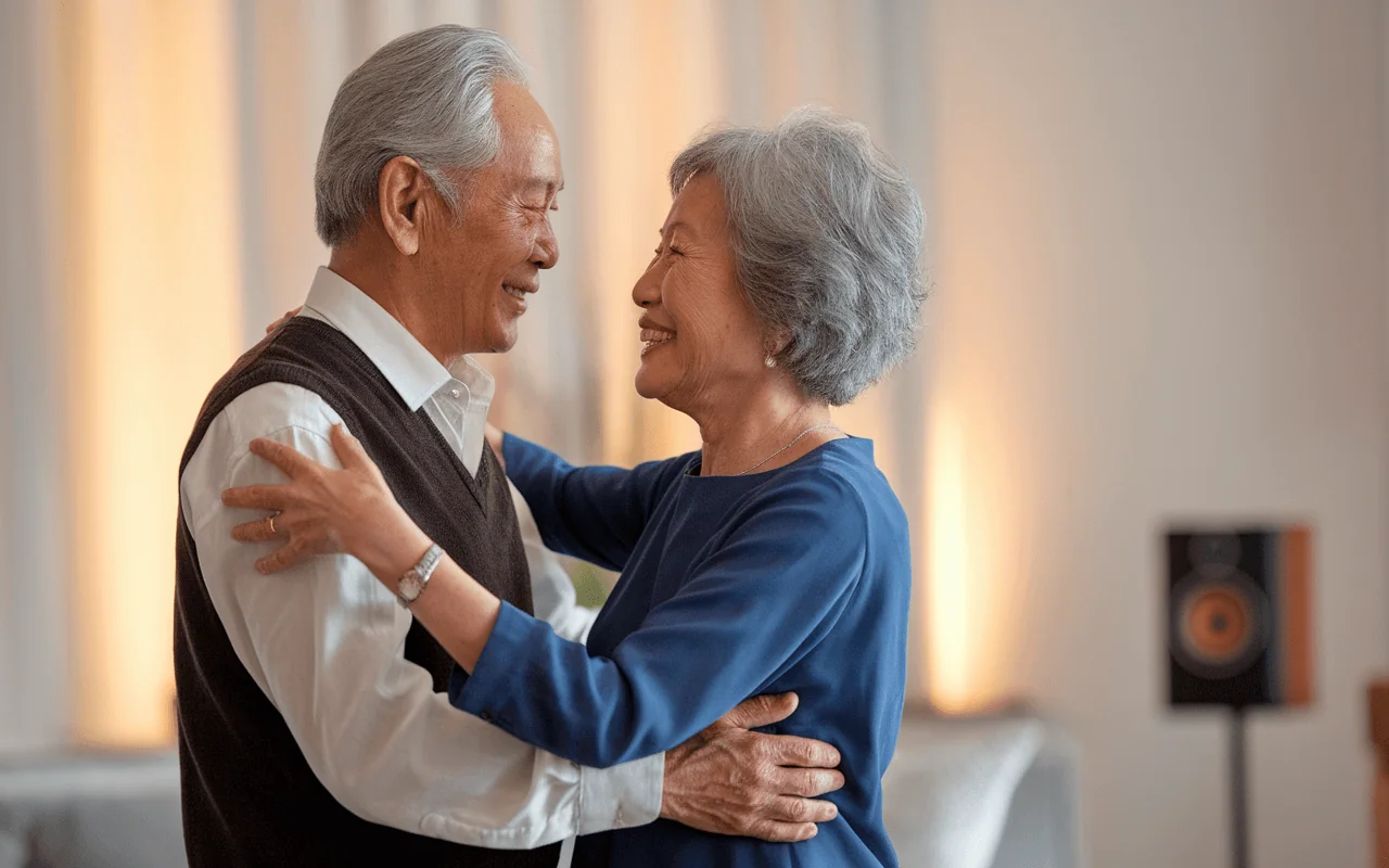 Joyful elderly Asian couple dances together, smiling and embracing, representing mood support and healthy aging.