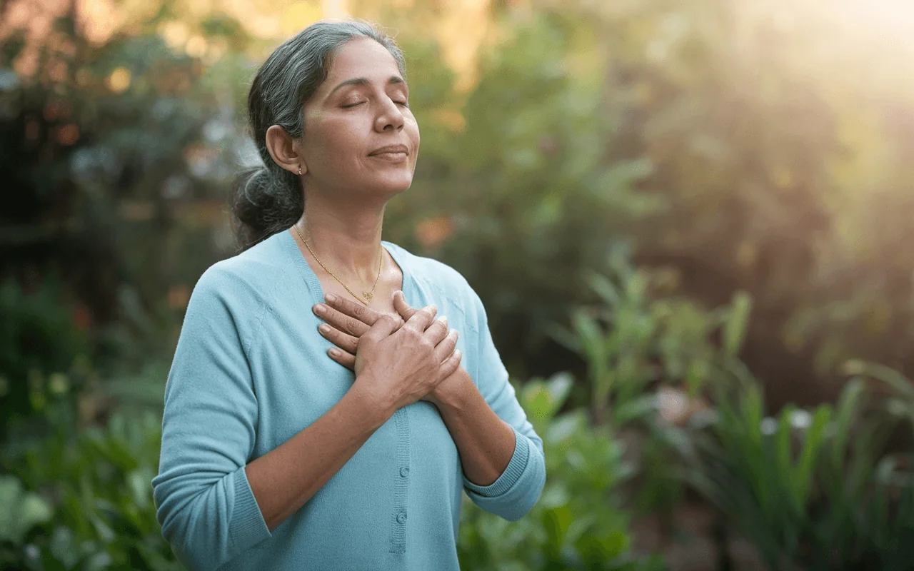 Middle-aged woman with eyes closed, hands on chest in a mindful pose, promoting healthy aging and well-being.
